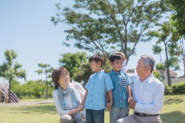 公園で微笑むシニア夫婦と孫