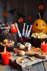 Halloween trick or treat party. Funny delicious sweets and pumpkin on wooden background - muffins, cupcakes, marshmallows, popcorn, juice, jellies, candy.