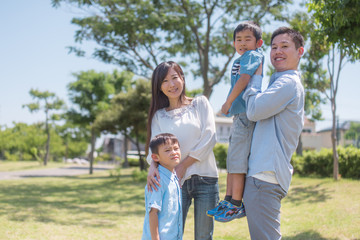 Fototapeta premium 公園で息子を抱き上げるお父さんと微笑む家族