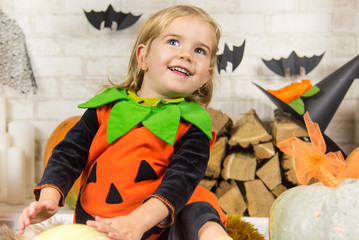 Funny child girl in pumpkin costume for Halloween with pumpkins and holiday attributes. Happy Halloween! The concept of Halloween, funny face.