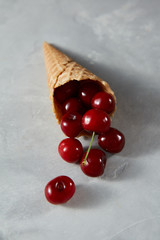 Summer fruits ripe red cherries in a wafer cones on a gray stone table. Vegetarian raw detox food.
