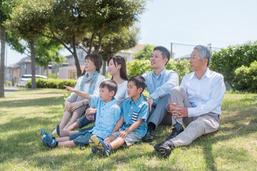 Obraz premium 公園で芝に座り遠くを眺める家族