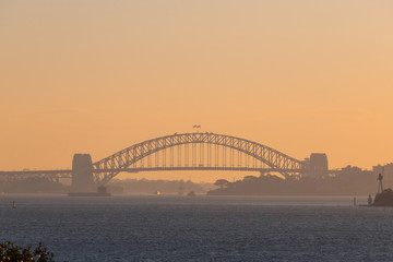Sydney Harbour Bridge in a hazy sunset sky.