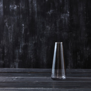 Transparent glass vase empty on a black wooden table, background.