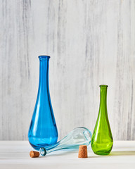 The colorful empty glass bottles with stoppers for saving natural homemade wine on a gray background, a table