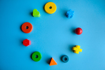 child creativity art and handcraft. construction kits for fine motor skills development. colorful wooden pieces or plastic details in a circle on blue background.