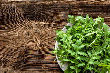 Green vegetables. Organic fresh arugula leaves on plate, vegan food concept