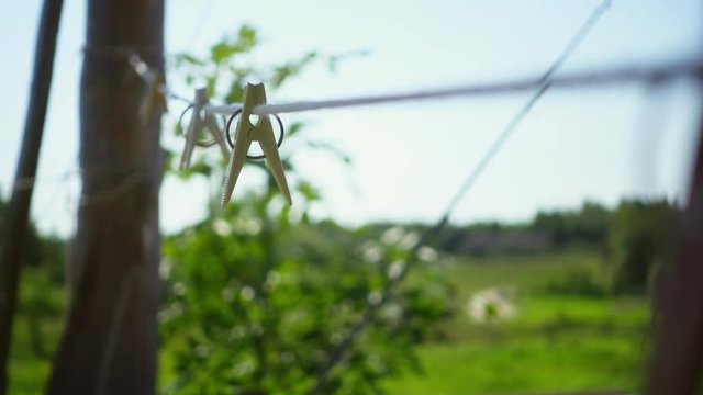 Romantic rural landscape with green field at daylight. Clothes pins on rope swaying in wind. Beautiful countryside place in summer day. Summertime romantic nature scene. Outdoor relaxing concept