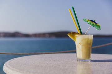 Cold glass of Pina Colada stand on table near the sea