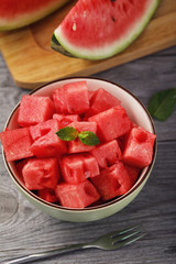 Full plate of sliced ​​pieces of ripe watermelon with mint on a wooden table © Sergey Chayko