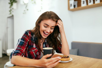 Happy Woman Using Phone In Cafe