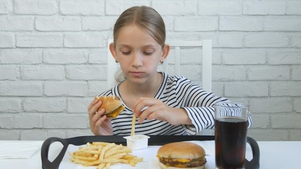 Child Eating Hamburger in Restaurant, Kid Eats Junk Fast Food, Girl Taste Fries © CreativeZone