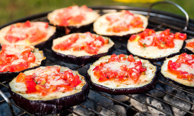 Eggplant with tomato and parmesan cheese on BBQ vegan grill.