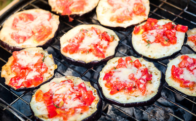Eggplant with tomato and parmesan cheese on BBQ vegan grill.