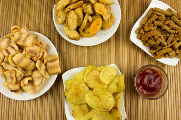  Snacks and potato chips on a plate. Wooden table. Salty food for beer