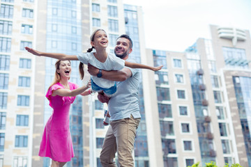 Strong dad. Delighted nice man holding his daughter while playing with her