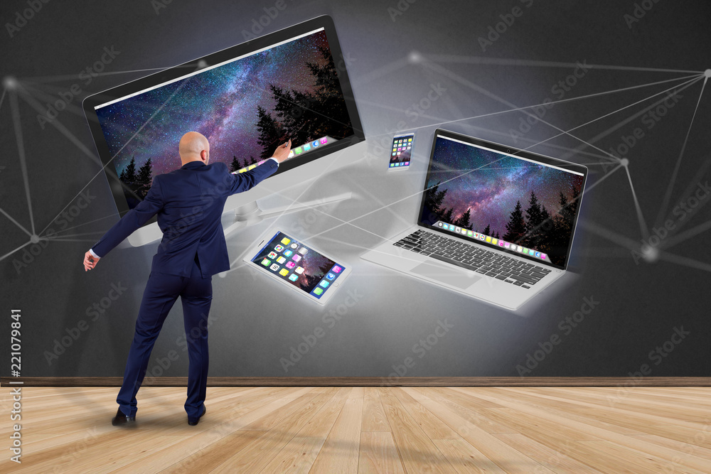 Poster businessman in front of a wall with devices like smartphone, tablet or computer flying over connecti