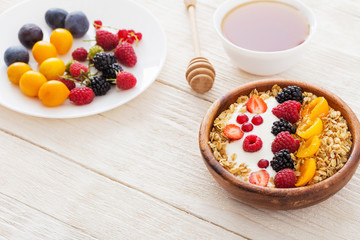 granola with berries on white wooden background