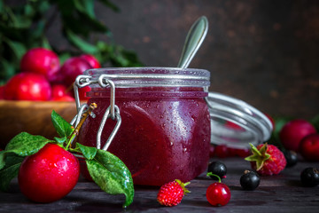 homemade jam in a glass jar of various berries and plums on a dark  background.Healthy food, diet, detox, clean eating and vegetarian concept with copy space.