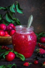 homemade jam in a glass jar of various berries and plums on a dark  background.Healthy food, diet, detox, clean eating and vegetarian concept with copy space.