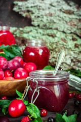 homemade jam in a glass jar of various berries and plums on a dark  background.Healthy food, diet, detox, clean eating and vegetarian concept with copy space.