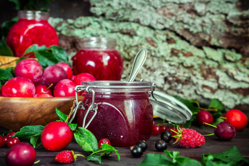 homemade jam in a glass jar of various berries and plums on a dark  background.Healthy food, diet, detox, clean eating and vegetarian concept with copy space.