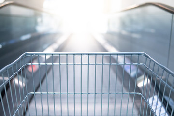 Empty shopping cart (trolley) on travelator or escalator in supermarket or grocery store.
