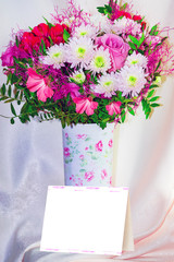 Bouquet of pink and white flowers in a light tall vase on a background of yellow and pink fabric, background, blank for Valentine's day cards
