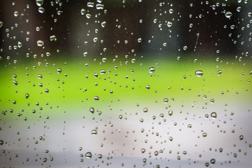 Naklejka na ściany i meble Water droplets on glass with green bokeh