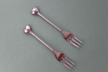 two silver heart shape forks side by side 