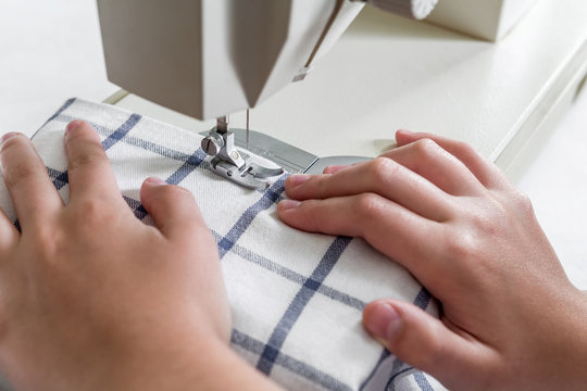 Hands of a seamstress on a sewing machine in the process of sewing with a copy of the space