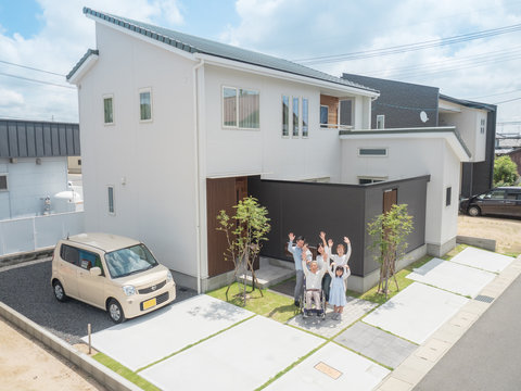 自宅前で手を振る三世代家族