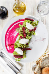 Healthy italian salad with beetroot, lettuce leaves and cheese feta and dressing with oil and mustard seeds. Top view