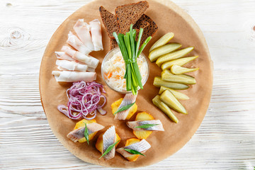 Sandwich on fried potatoes with herring, green onion. Tasty appetizer with sauerkraut, pickled cucumber, mustard on wooden Board. Rye bread and lard