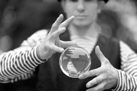 Transparent magic ball with reflection in the open palms of the clown
