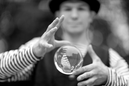 Transparent magic ball with reflection in the hands of a clown