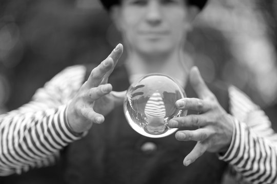 Transparent magic ball with reflection in the hands of a clown