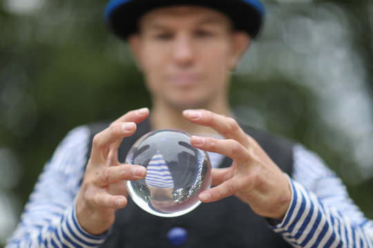 Transparent magic ball with reflection in the hands of a clown
