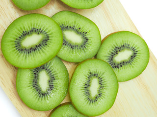 Slice of fresh juicy delicious and healthy kiwi fruit on wooden chopping board, isolated on white background.
