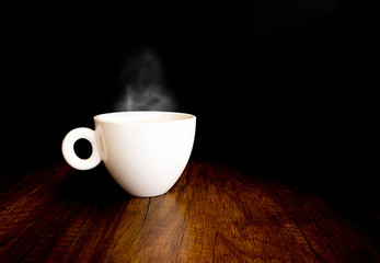Hot coffee with steam out of a cup, on wooden table, and black background