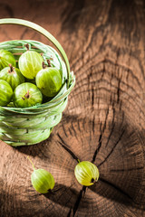 Heap of gooseberries in basket on vintage wooden board