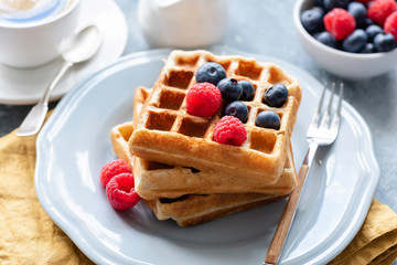 Belgian waffles served with fresh berries on a plate, closeup view. Tasty breakfast