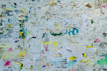 Board with tattered ads. A lot of ragged ads. Ragged paper ads. Advertising signboard with torn paper. © Andrii Chagovets