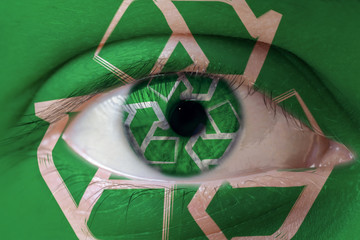 Human face painted with recycle symbol on the face and the iris. The concept of the ecologycal...