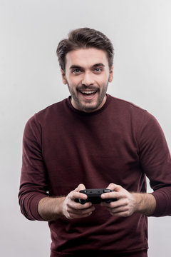 Man with joystick. Emotional handsome young man holding joystick while enjoying video games on image without face retouching