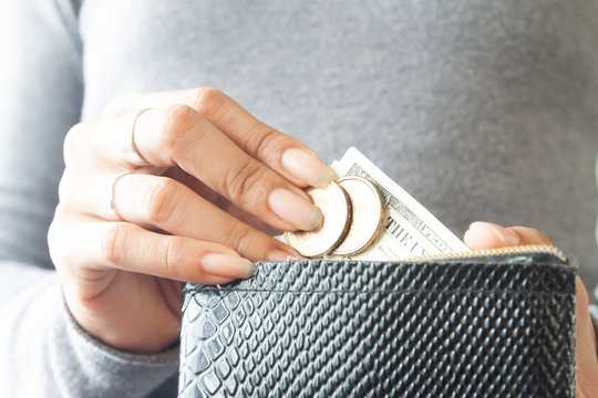 Woman holding wallet with coins and paper currency