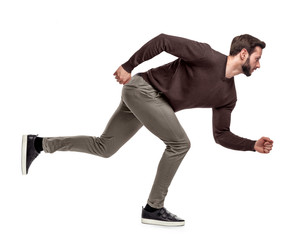 A fit bearded man in casual sweater stands in a low running position with only one foot on the...