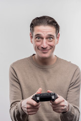 Video game. Dark-eyed man wearing beige sweater holding joystick playing video game on image...