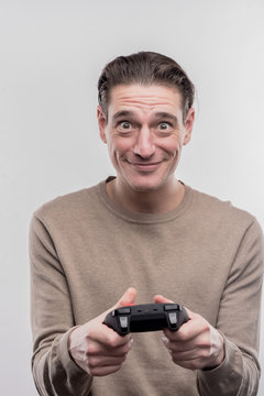 Video game. Dark-eyed man wearing beige sweater holding joystick playing video game on image without face retouching