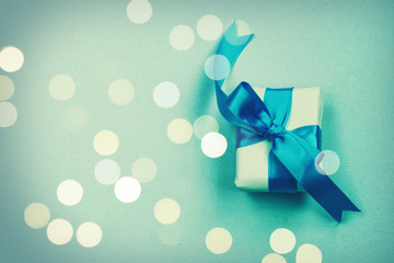 wrapped gift box with blue bow, on paper texture background